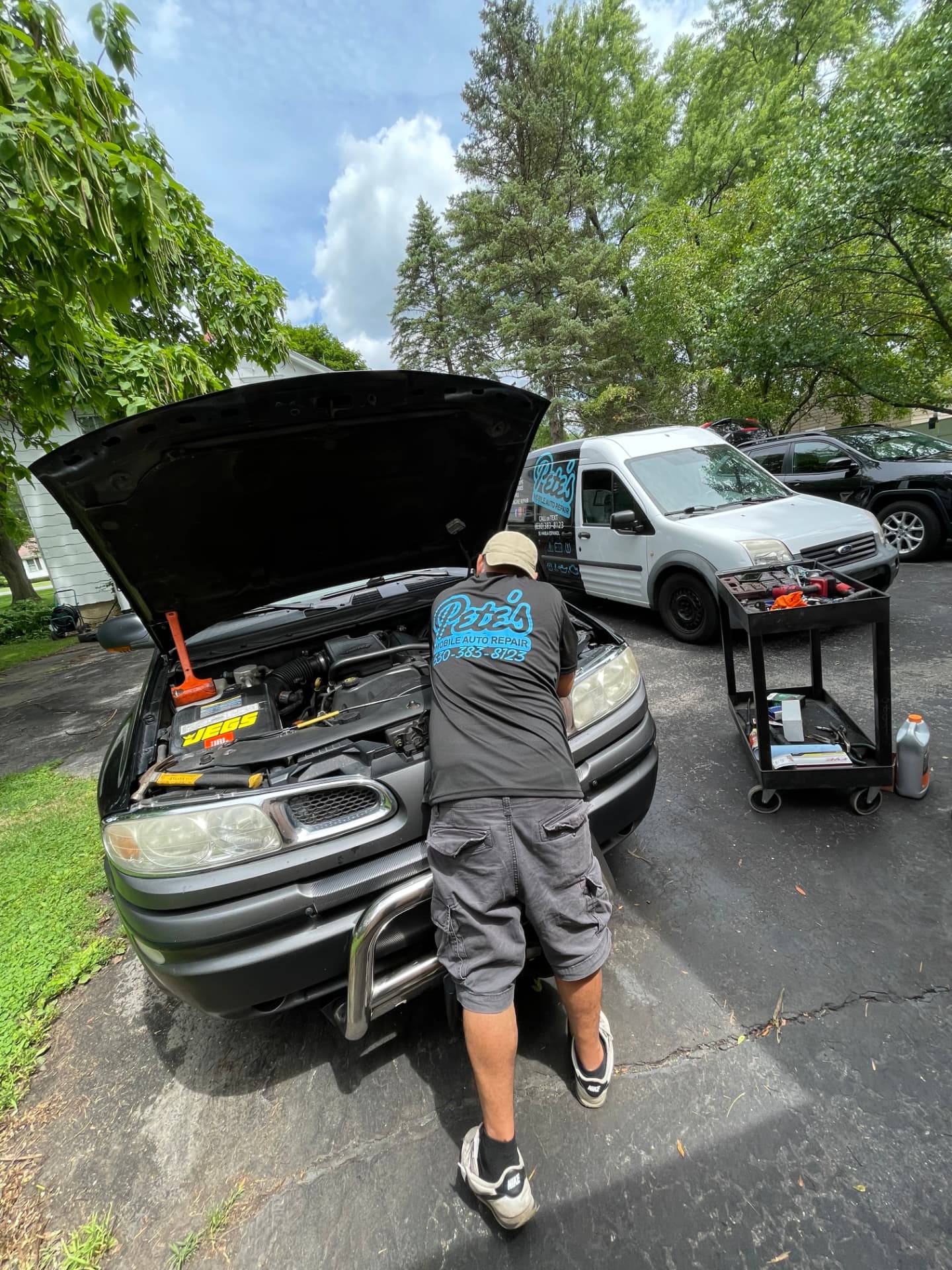 Pete's technician working under the hood with the service van and tool cart on-site